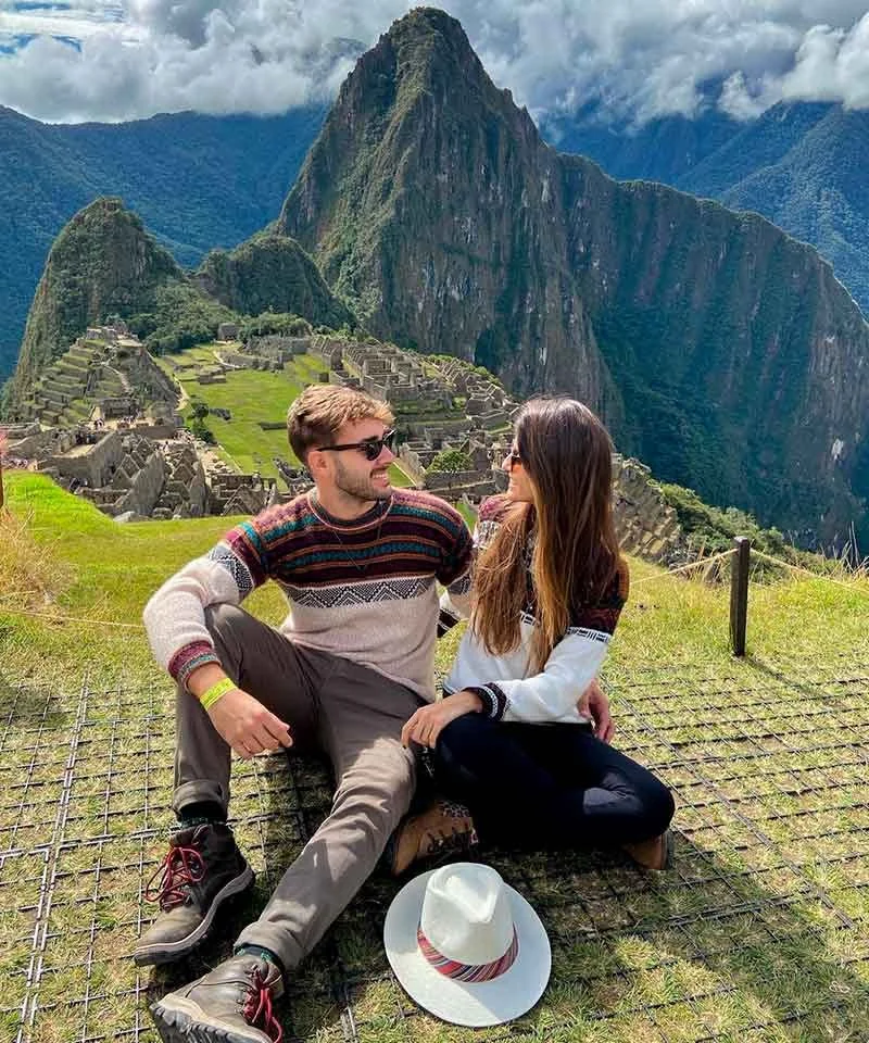Casal apaixonado na cidadela inca de Machu Picchu com montanhas ao fundo, um destino essencial nos pacotes de viagem para o Peru.
