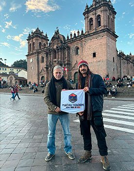 Amigos na praça de Armaz de Cusco com a bandeira da Machu Viagens Peru